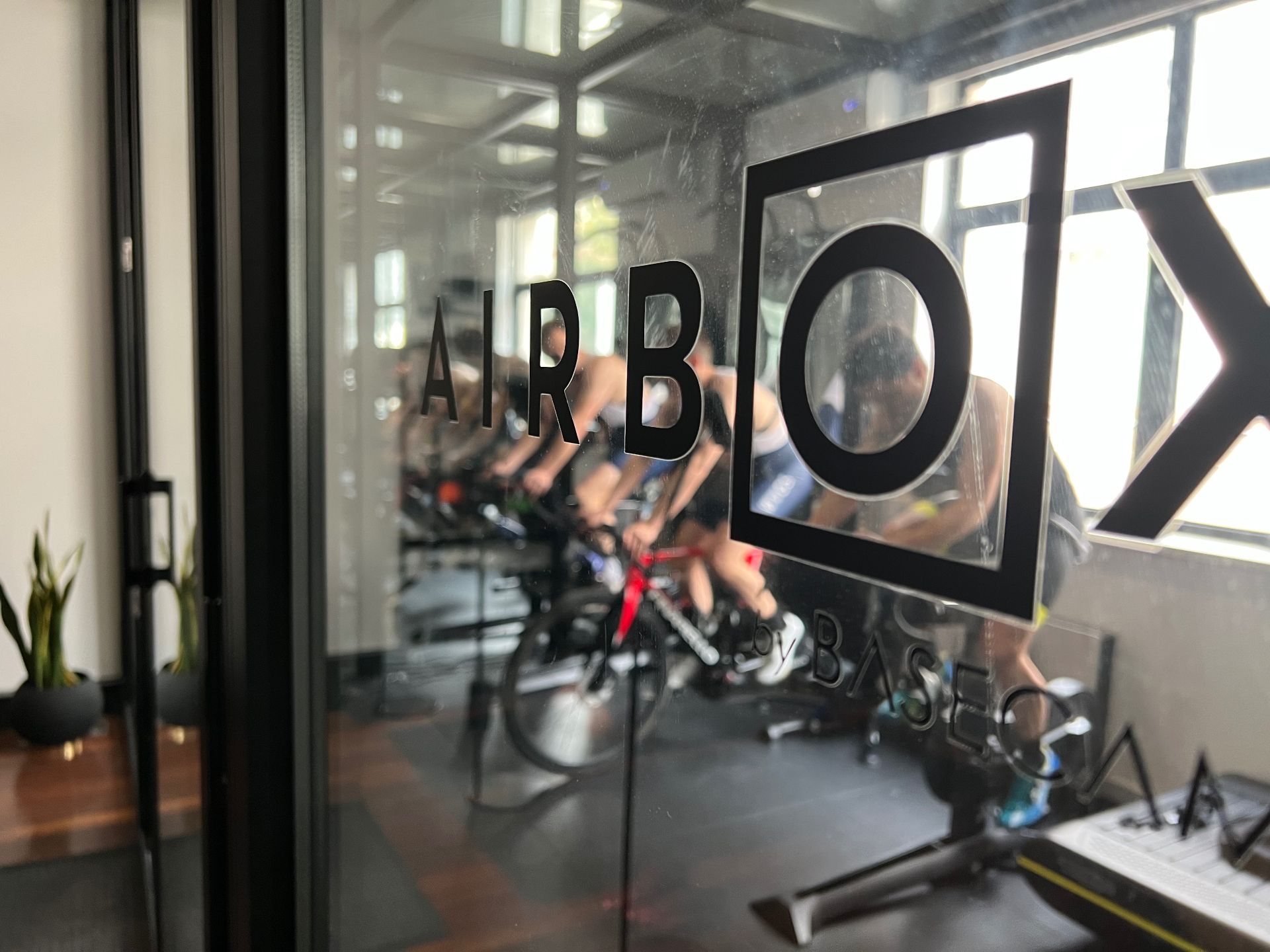 Athletes on indoor cycling trainers in a high-performance Airbox studio — the kind of controlled exercise environment used for physiological testing and return-to-sport conditioning.