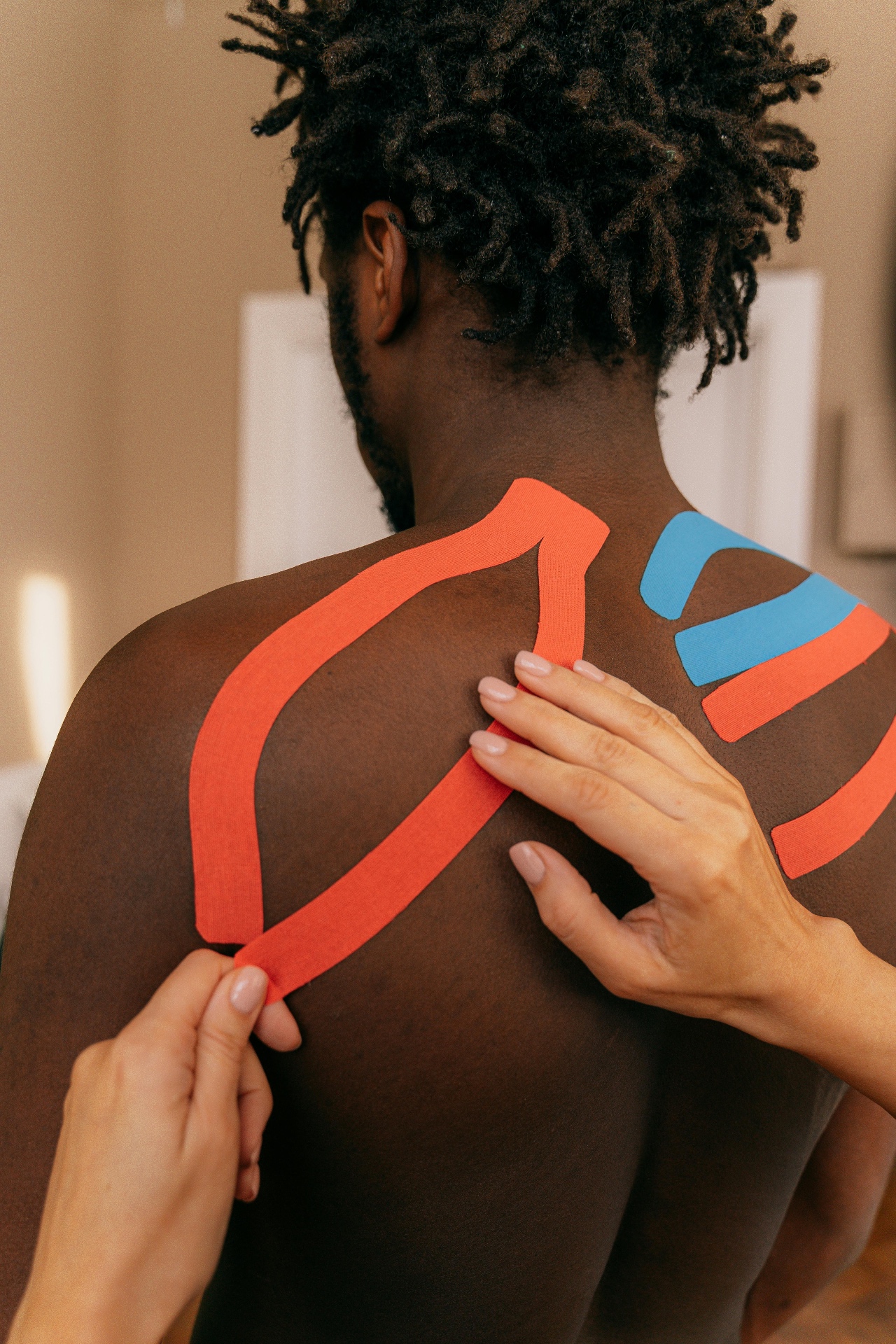 Physiotherapist applying kinesiology tape to an athlete's shoulder — support, feedback and offloading for return to sport.