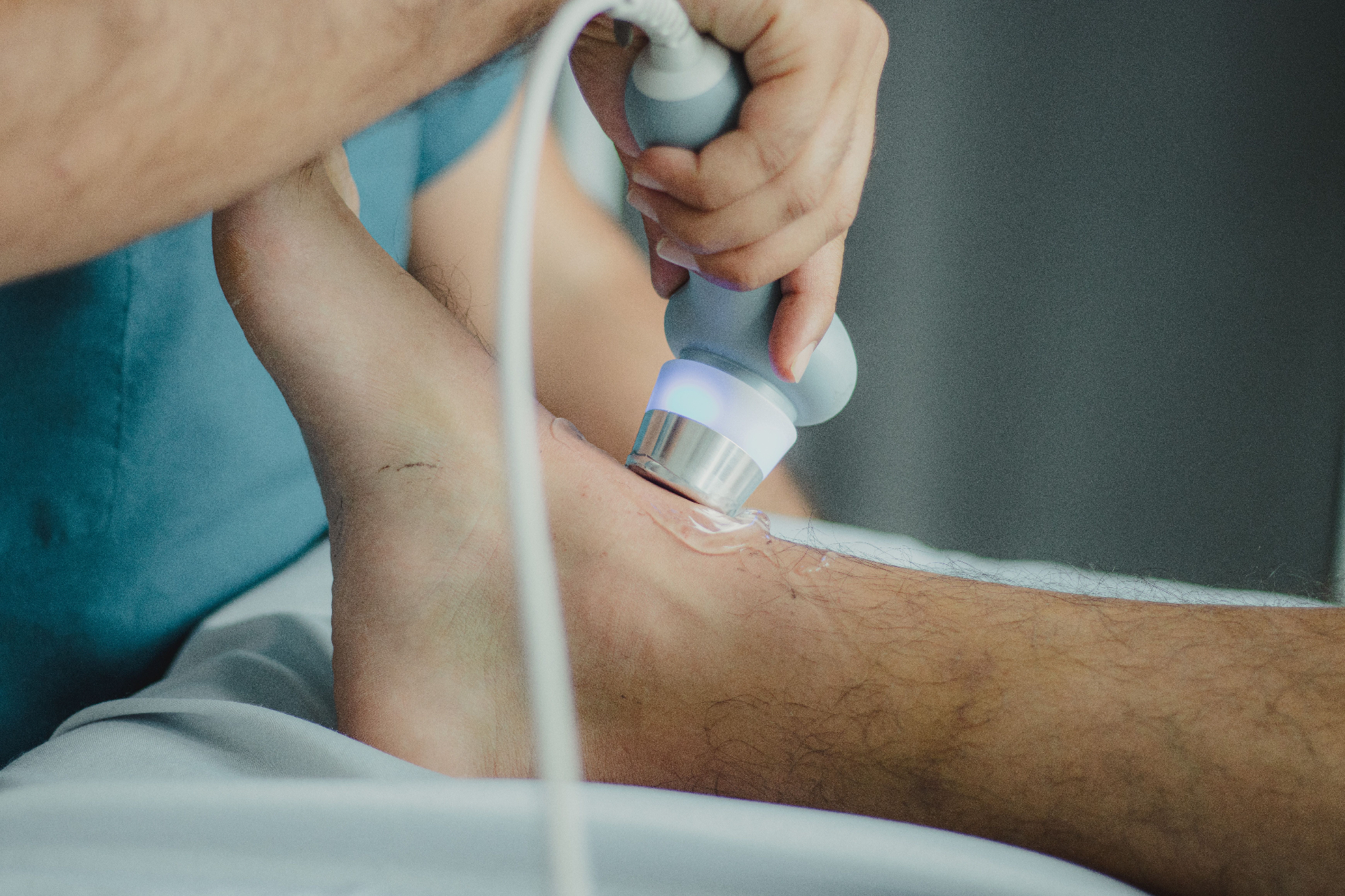 Close-up of a shockwave therapy device applied to a patient's knee — precise, targeted treatment for chronic tendon pain.