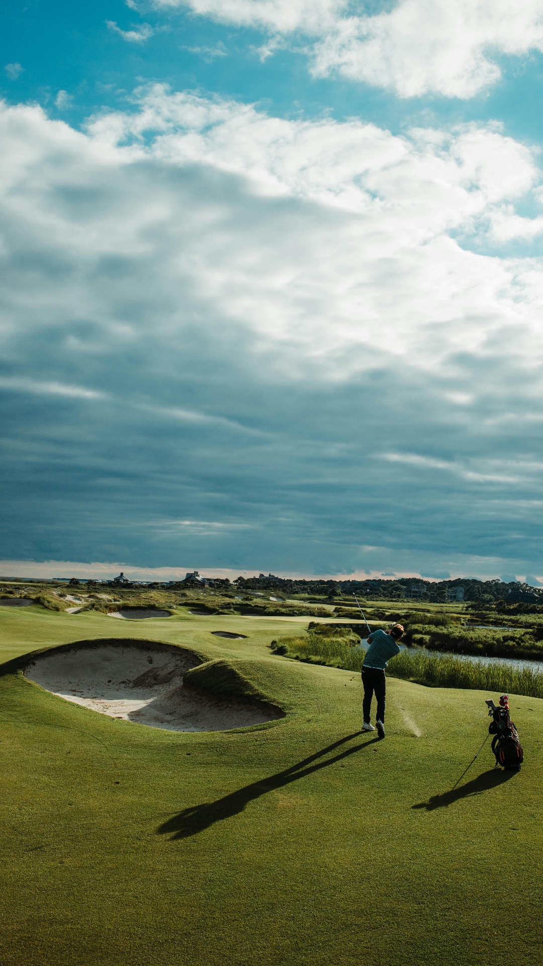 Golfer completing a full swing on a coastal course — TPI screening links the body to the golf swing.