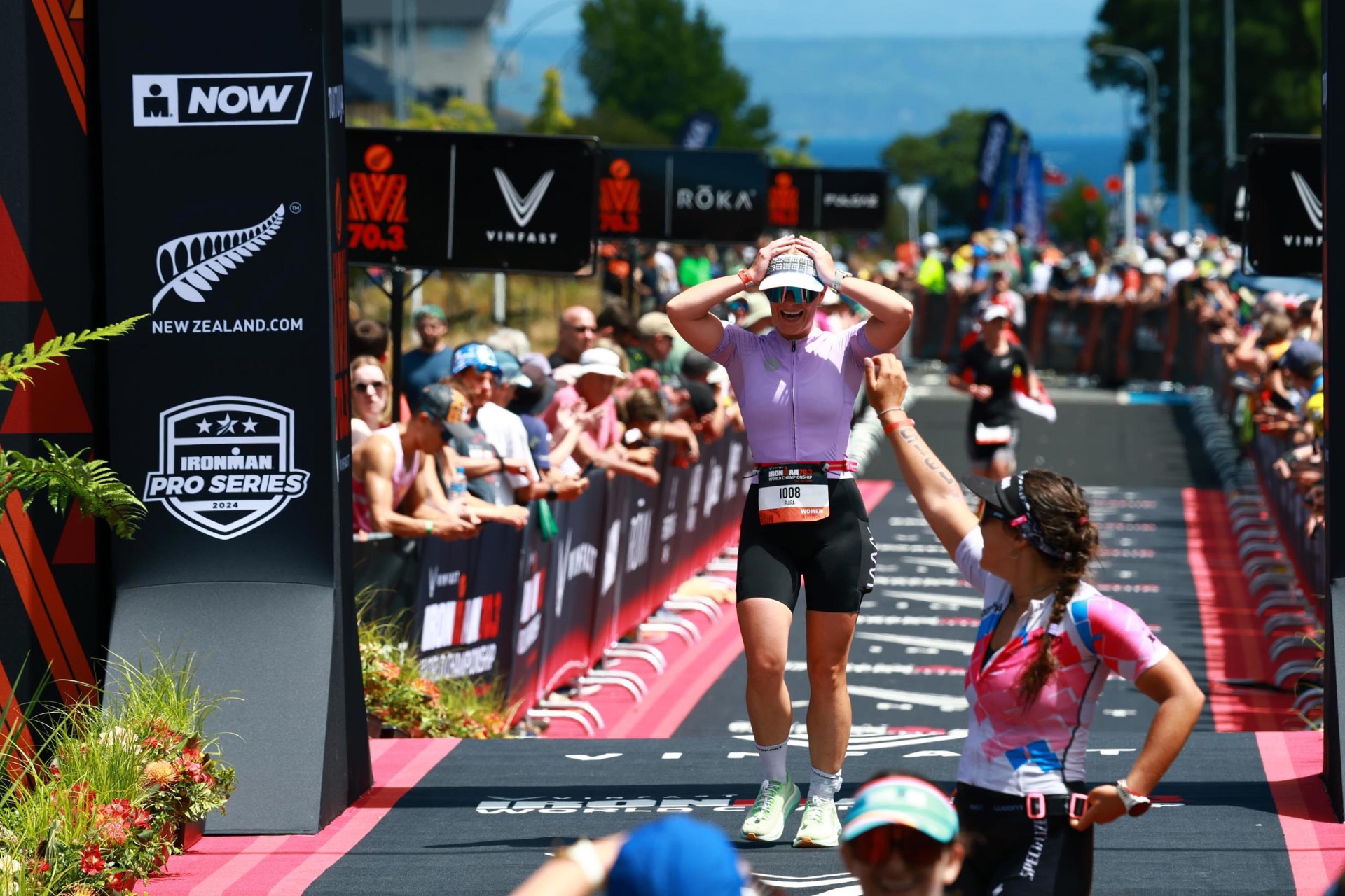 Flora Muijzer crossing the finish line at the Ironman 70.3 World Championship in Taupō, New Zealand, arms raised in celebration