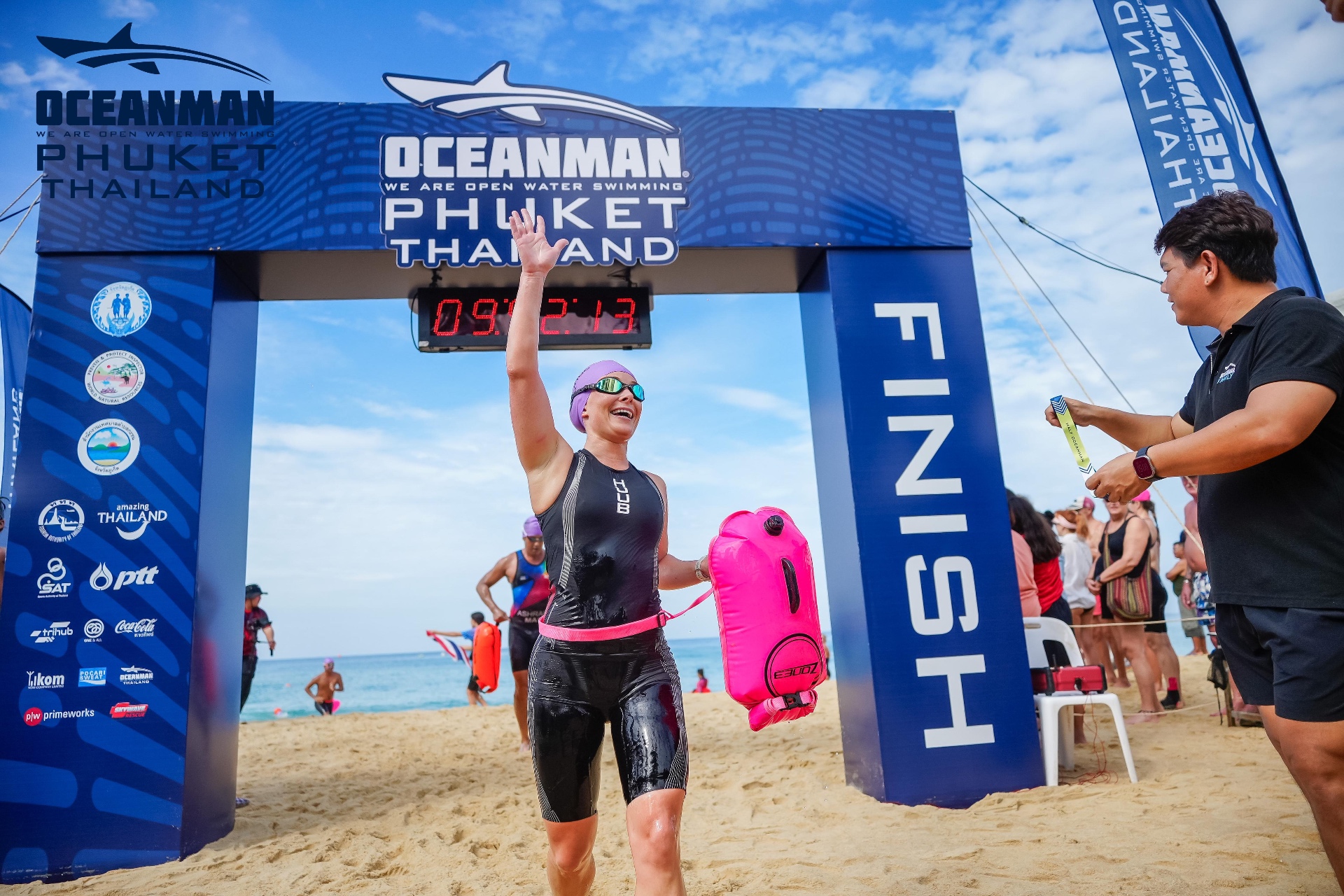 Flora Muijzer smiling and waving at the OceanMan Phuket finish line after qualifying for the OceanMan World Championship